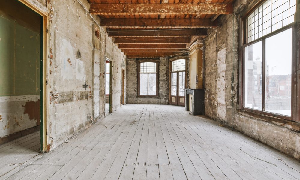 An empty room with wooden floors and brick walls in an old house in need of renovation